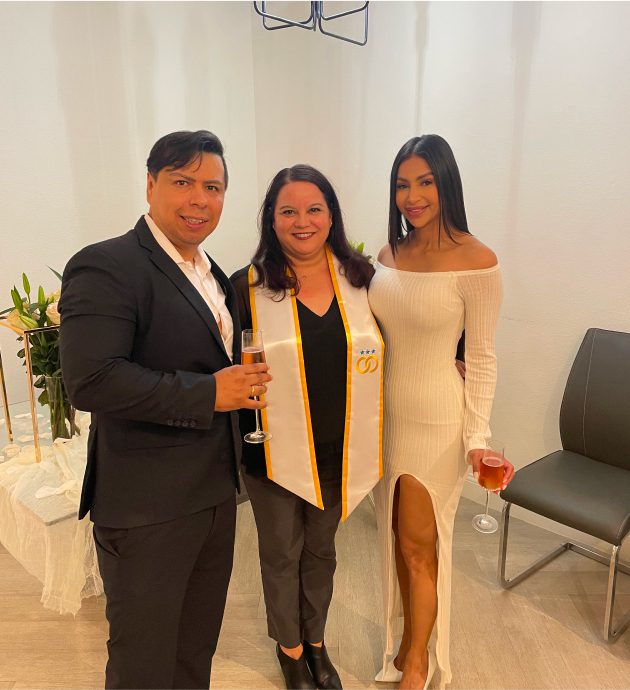 Three people celebrating with drinks indoors.